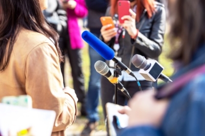 Journalist filmt mit Smartphone auf einer Pressekonferenz